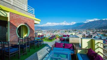 An outdoor terrace with seating and a view of snow-capped mountains.