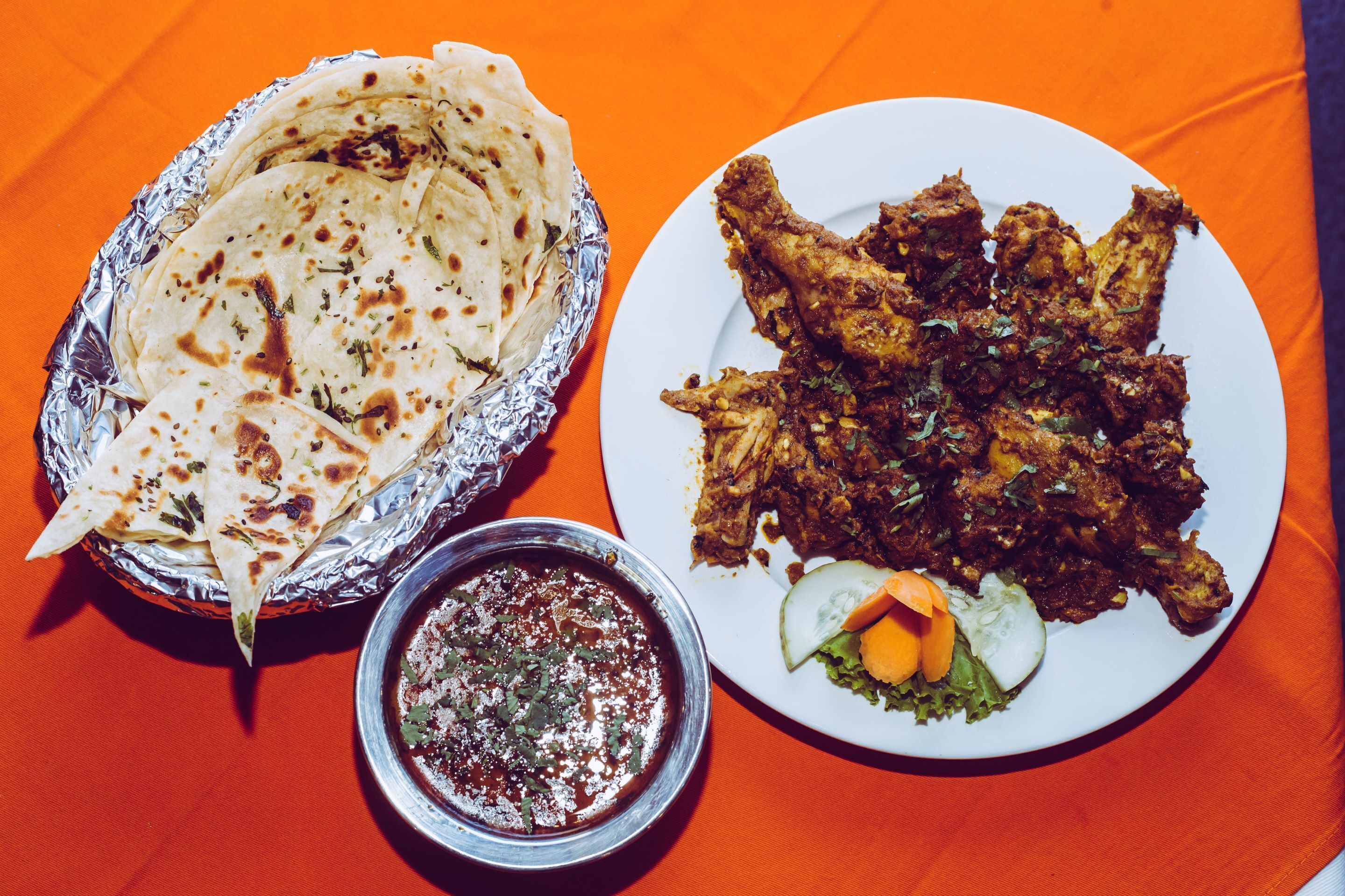 Un plato de comida con pan naan y una salsa acompañante.