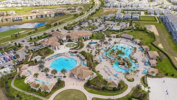 An aerial view of a resort with multiple swimming pools, a central pavilion, and surrounding villas. - Upstay 9BR Villa w Pool & Cinema—Epic Universe (Championsgate)