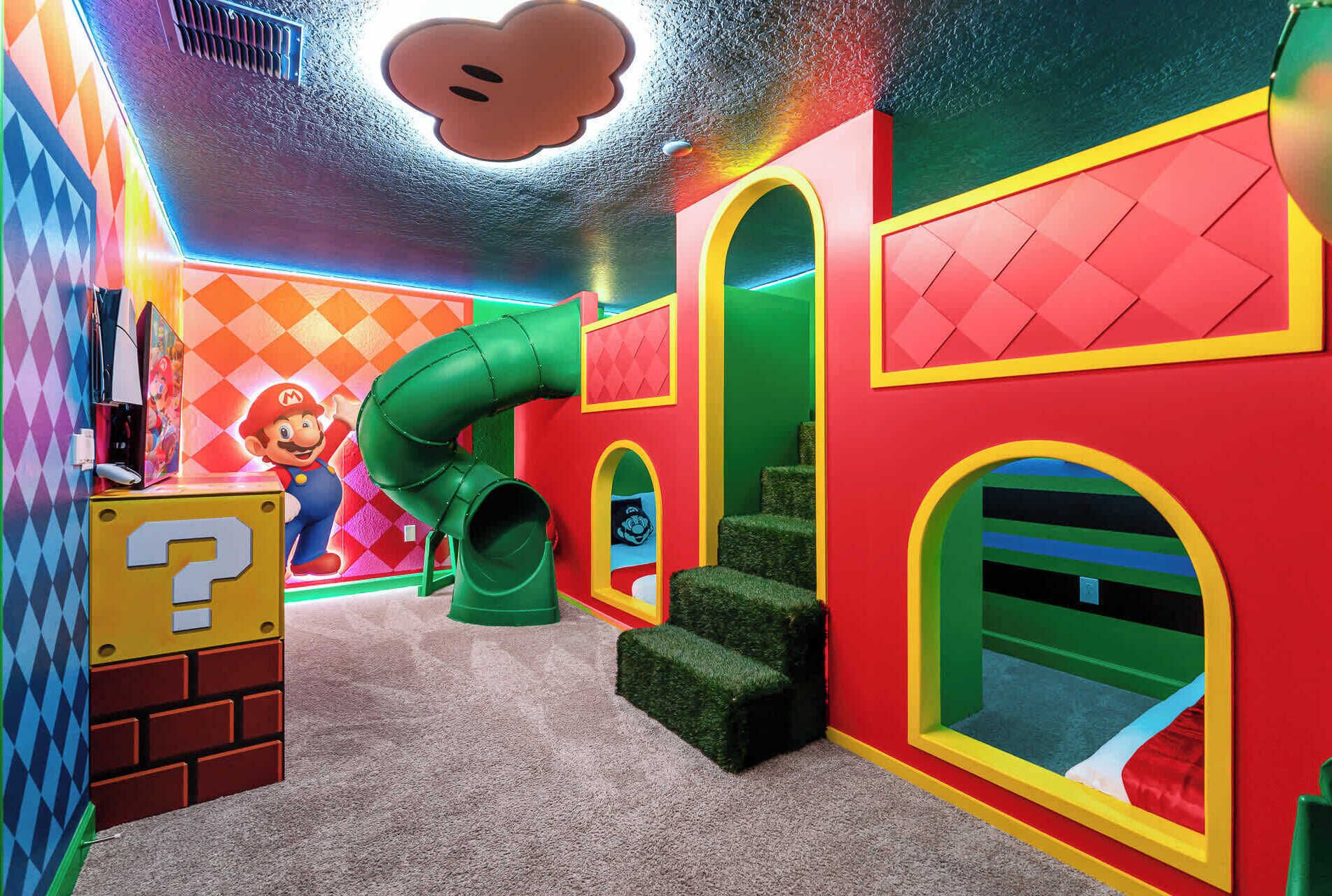 A colorful play area with a Mario-themed backdrop, a green slide, and a question mark-shaped play structure.