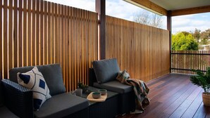 A covered outdoor seating area with two sofas, cushions, a tray with bowls, and a potted plant. - Wynvale Cottage @ Hepburn (Hepburn)