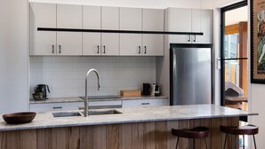 A modern kitchen with white cabinets, a stainless steel refrigerator, a sink, and a wooden countertop. - Wynvale Cottage @ Hepburn (Hepburn)