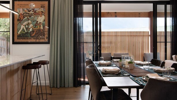 A dining area with a table set for four, a bar counter with stools, and a large window with a view of the outdoors. - Wynvale Cottage @ Hepburn (Hepburn)