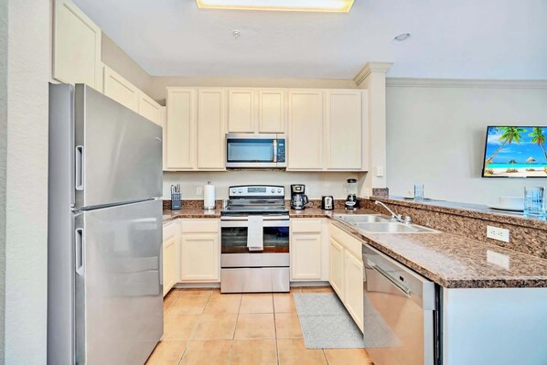 A modern kitchen with white cabinets, stainless steel appliances, and a granite countertop.