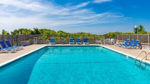 A rectangular swimming pool with clear blue water, surrounded by blue and white lounge chairs. - Seabound - Oceanfront Condo + Steps to the Sand (Atlantic Beach)