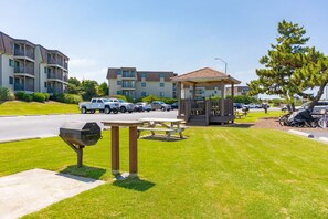 A parking lot with a gazebo, picnic tables, and a barbecue grill. - Seabound - Oceanfront Condo + Steps to the Sand (Atlantic Beach)