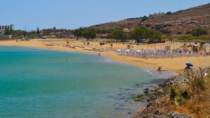 A beach with clear turquoise water, a sandy shore, and a hotel in the background. - Stefi Deluxe Villas - Avgi Private Pool Retreat (Anopoli)