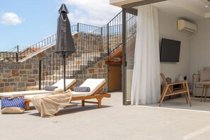 Property Exterior with Lounge Chairs and Open Views – Stylish outdoor living space with stone surroundings.