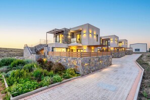 A modern multi-story house with a stone facade, large windows, and outdoor lighting.