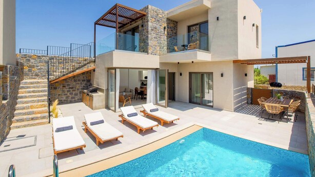 Una moderna casa a due piani con piscina, area salotto esterna e scalinata in pietra.