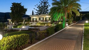 Eine moderne Villa mit Pool, Sitzgelegenheiten im Freien und einem gut beleuchteten Weg.
