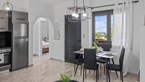 Uma cozinha moderna com geladeira embutida, área de jantar com mesa e cadeiras, e vista pela janela.