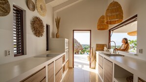 Una cocina moderna con armarios blancos, un ventanal y vistas al exterior.