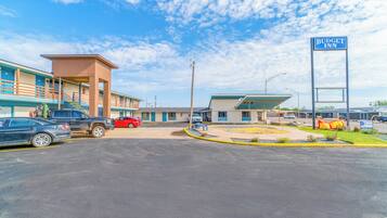 A motel with a blue sign, a parking lot, and a small garden area.