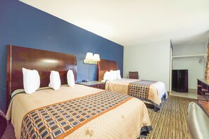 Een hotelkamer met twee bedden, een bureau, een stoel, een lamp en een spiegel.