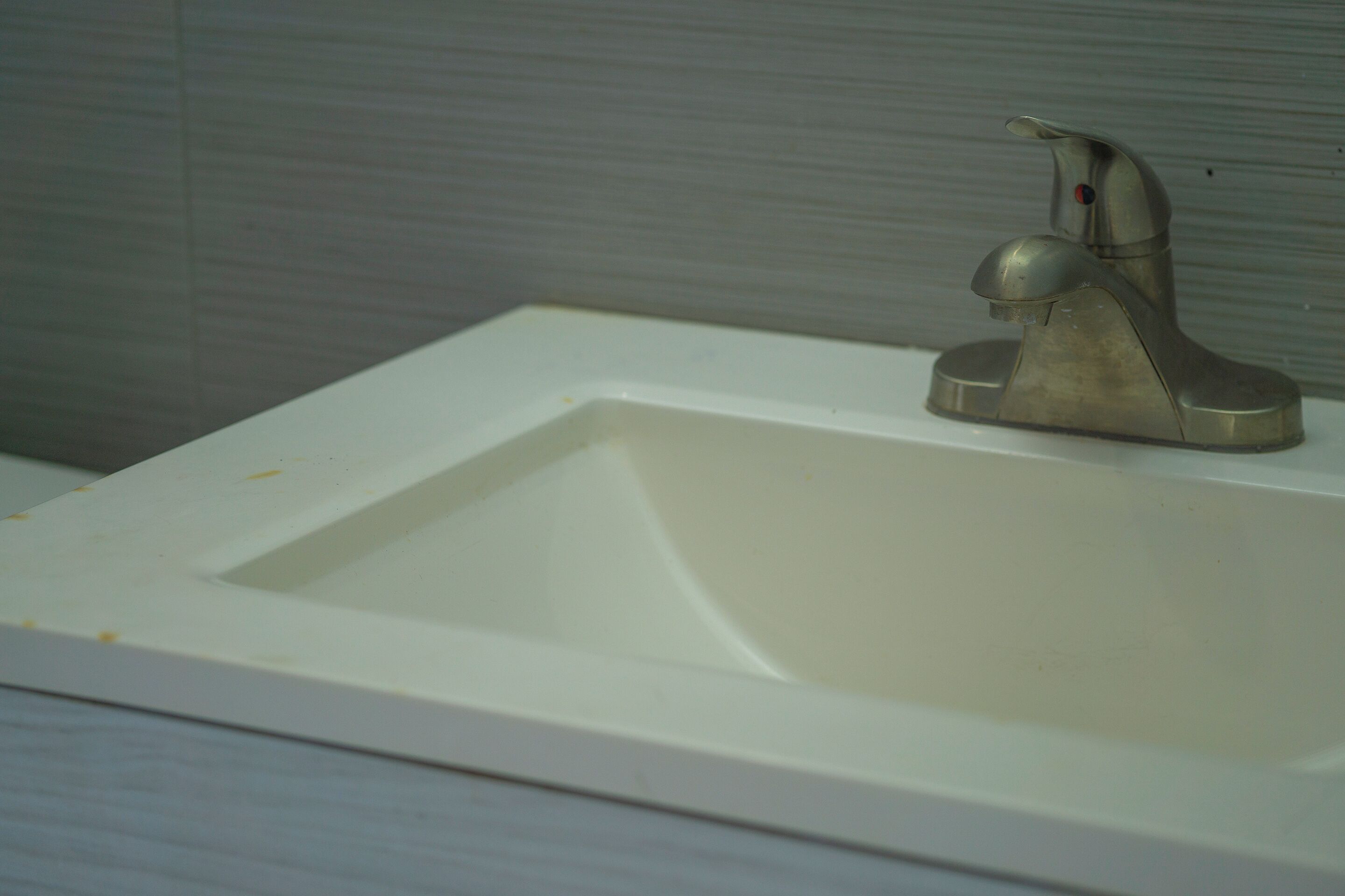 Un lavamanos de baño con un grifo moderno y un lavabo blanco.