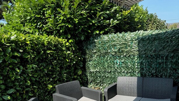 An outdoor seating area with wicker furniture and a patterned rug.
