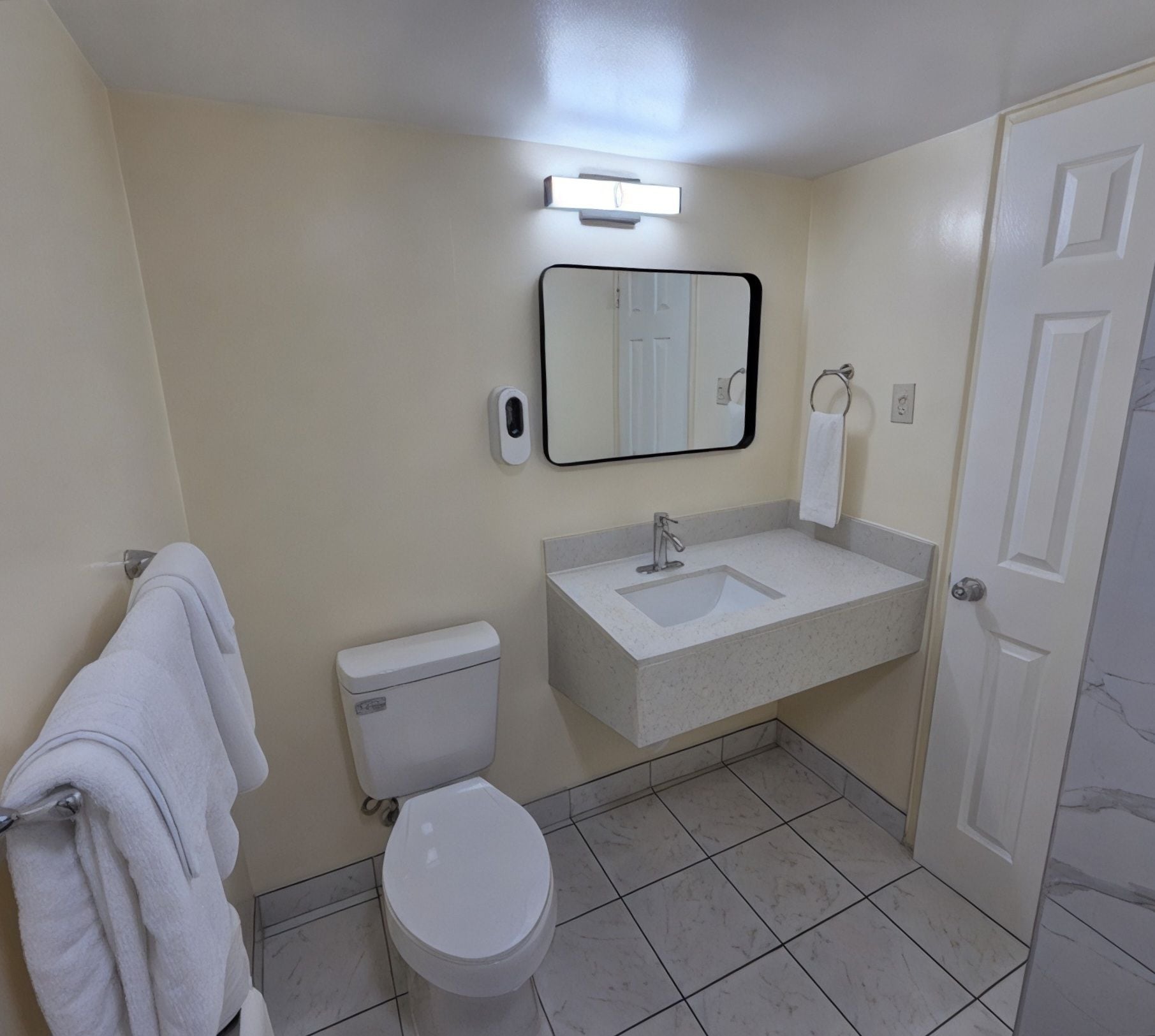 Une salle de bain équipée de toilettes, d’un lavabo, d’un miroir et d’un porte-serviettes.
