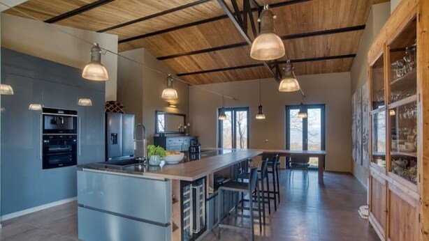 Een moderne keuken met een centraal eiland, roestvrijstalen apparatuur en hanglampen.