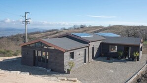 Een modern huis met twee verdiepingen, een grindpad en zonnepanelen op het dak.