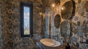 Een badkamer met een groot ovaal wastafel, een raam en wanden met een bloemenmotief.