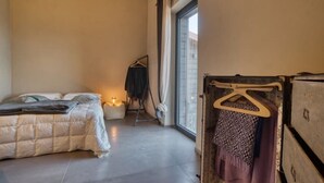 Een slaapkamer met een bed, een hangstoel, een kledingkast en een groot raam.