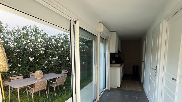 A narrow corridor with a sliding glass door leading to a patio area with a table and chairs. - Villa 60m² with garden, air conditioning and parking - up to 6 people (La Roquette-sur-Siagne)