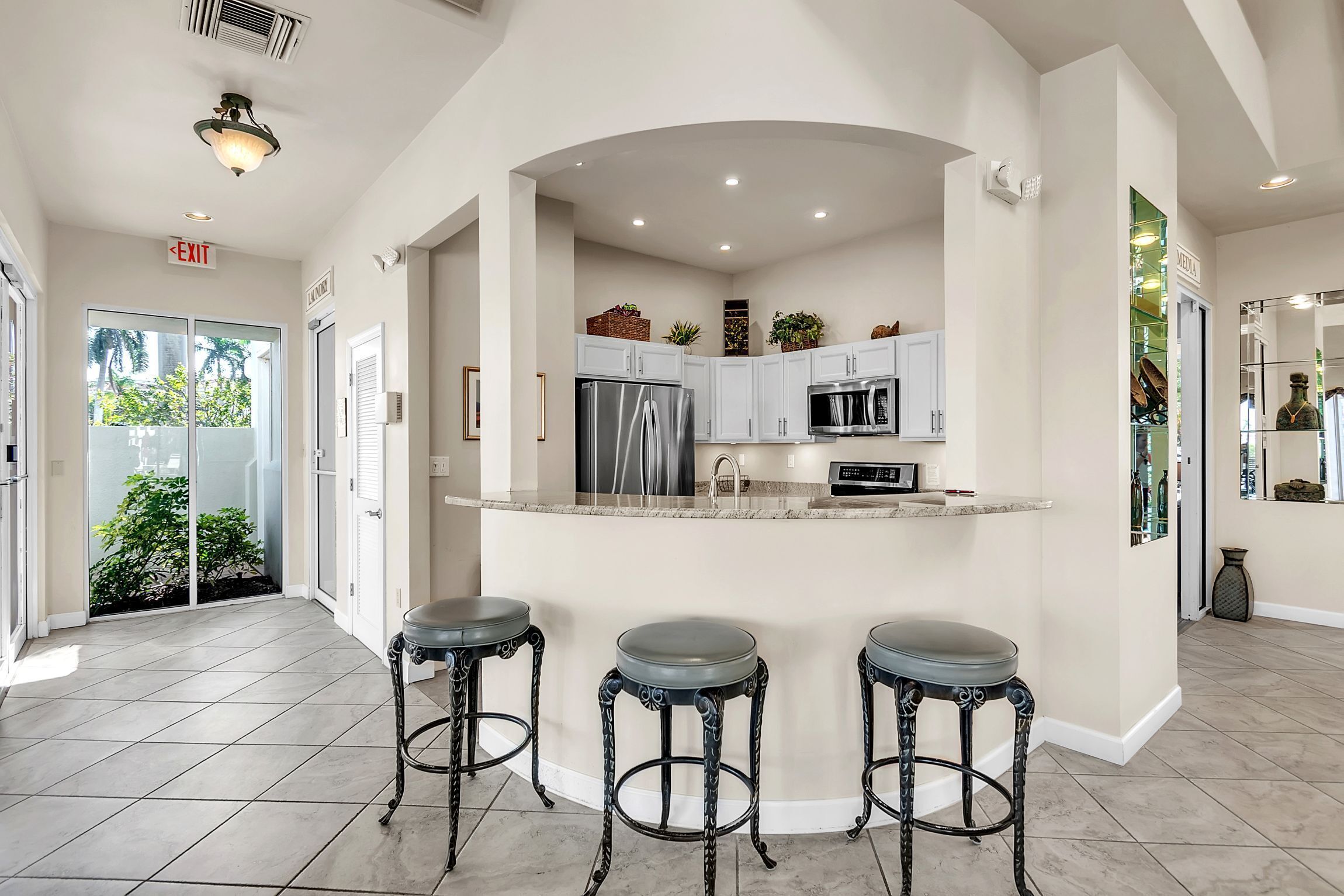 A modern kitchen with a central island, stainless steel appliances, and three bar stools.