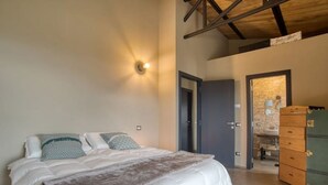 A bedroom with a bed, a dresser, and a bathroom visible through an open door. - PaterMater b&b - Lana Room (Castell'Azzara)