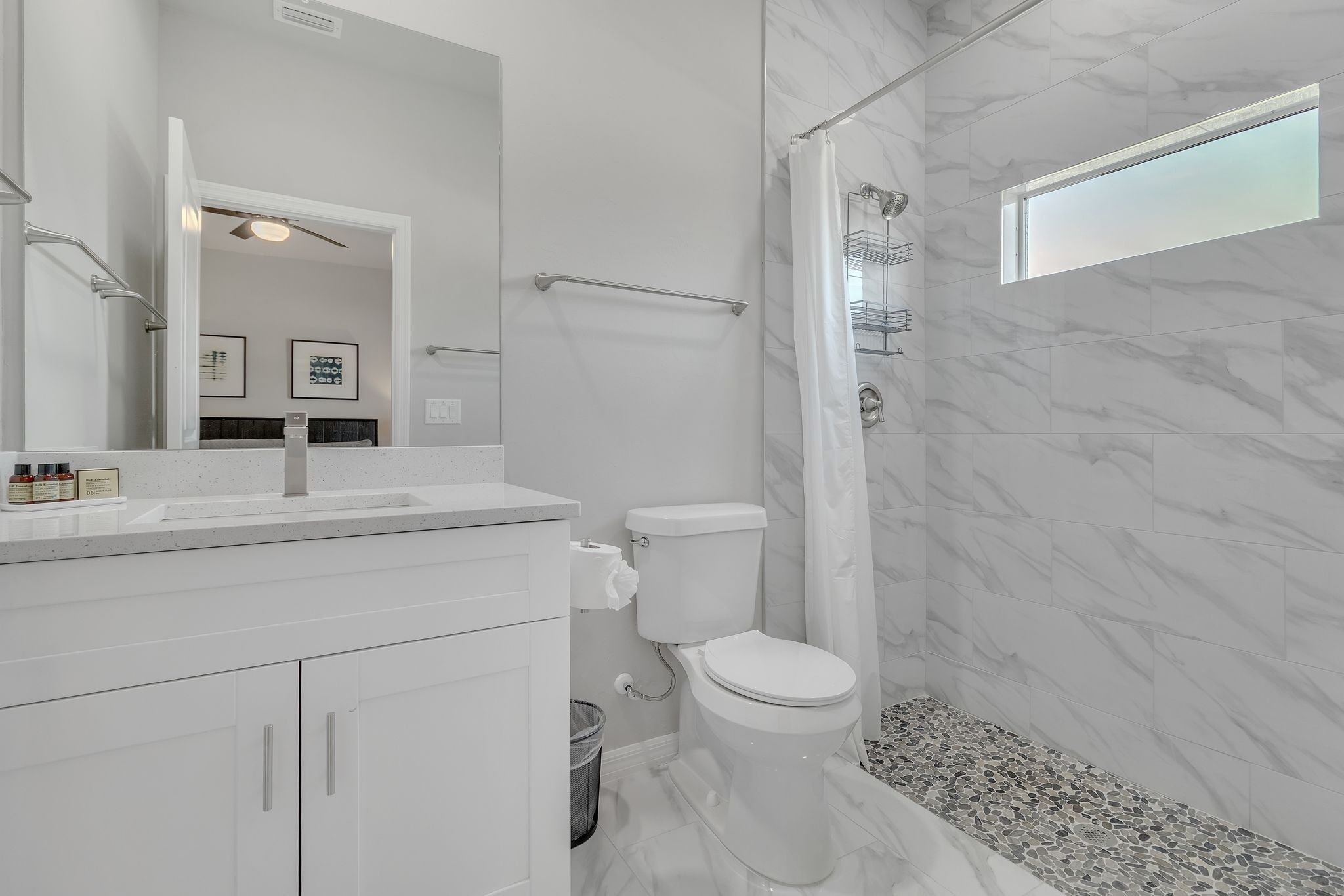 Un bany modern amb un lavabo, vàter i plat de dutxa blancs.