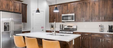 A modern kitchen with wooden cabinets, stainless steel appliances, and a central island with bar stools.