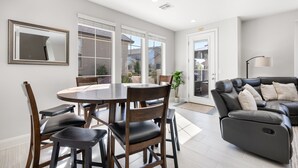 Un salon moderne comprenant une table à manger, des chaises, un canapé et une grande fenêtre.