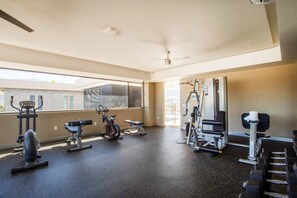 A gym with various exercise equipment, large windows, and a ceiling fan. - Top-Floor 2BR w/ Skyline Views, Pool & Gym (Puerto Vallarta)