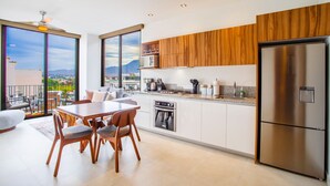 Une cuisine moderne dotée d’un grand îlot central, d’appareils électroménagers en acier inoxydable et de meubles de rangement en bois.