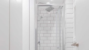 A modern bathroom with a glass-enclosed shower, a white toilet, and a washing machine. - Homely 2BD Flat W/private Patio Near Maida Vale! (London)