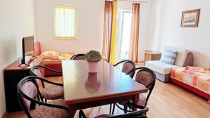 A compact living space with a dining table surrounded by chairs, a sofa, and a small bed.