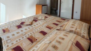 A bedroom with a bed, a television, a small cabinet, and a door leading to a bathroom.
