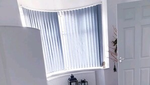 A room with a large window, a standing lamp, a patterned rug, and a door. - Beautiful 3-bed House in Birmingham (Birmingham)