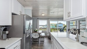 Une cuisine moderne avec des armoires blanches, des appareils en acier inoxydable et un plancher en bois.