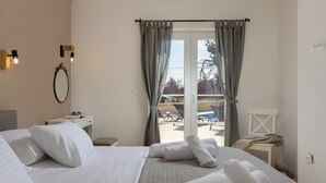 A hotel room with a bed, a bedside table, a mirror, and a view of an outdoor pool area through a sliding glass door. - Villa Mediterra Prima Zadarvillas (Nin)
