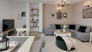 A modern living room with a grey sofa, a dining table with chairs, a TV, and a chandelier. - Villa Mediterra Prima Zadarvillas (Nin)