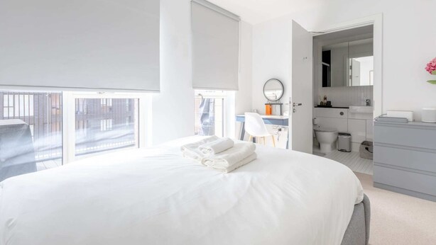 A modern hotel room with a large bed, a desk, and a bathroom. - Stylish 2BD Oasis W/balcony South East London! (London)