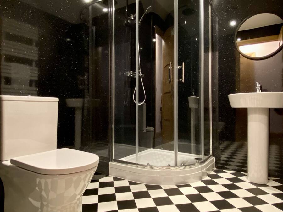 Een badkamer met een glazen douchecabine, een toilet en een wastafel.