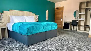 Una habitación de hotel con una cama, un escritorio, un armario y una alfombra estampada.