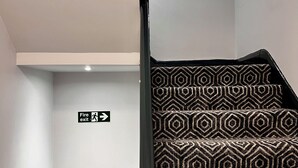 A staircase with a patterned carpet and a fire exit sign. - The Bath Rooms (Morecambe)