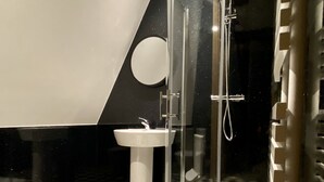 A bathroom with a checkered floor, a toilet, a sink, and a glass-enclosed shower. - The Bath Rooms (Morecambe)
