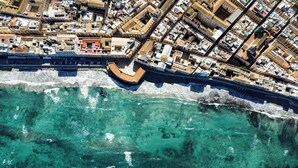 An aerial view of a coastal city with a prominent waterfront promenade and densely packed buildings. - House in the historic center near the port (Trapani)