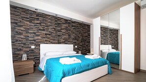 A modern bedroom with a large bed, a wooden nightstand, a mirror, and a wall with a patterned design. - House in the historic center near the port (Trapani)