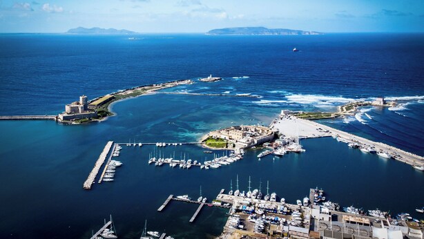 An aerial view of a coastal marina with boats, a lighthouse, and a fort. - House in the historic center near the port (Trapani)