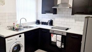 A compact kitchen with a washing machine, a stove, and a sink. - Fantastic Home! Football Fans -5 min to Stadium (Liverpool)